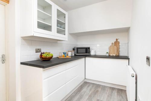 a kitchen with white cabinets and a black counter top at Central Basement Flat-Parking-By FabAccommodation in Bristol