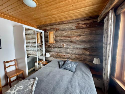 a bedroom with a wooden wall with a bed at Usva Cabins Ylläs - Sapara J 38 in Äkäslompolo