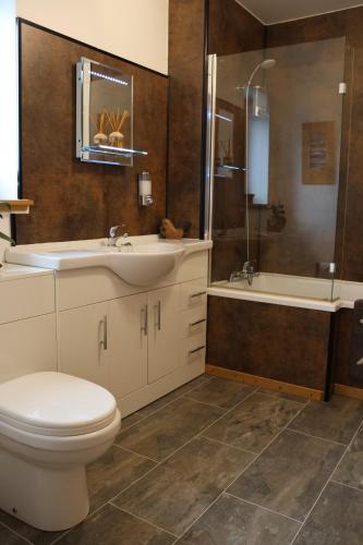 a bathroom with a toilet and a sink and a tub at Modern, eco friendly house in Kildonan on Skye in Flashader