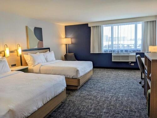 a hotel room with two beds and a window at Spark by Hilton Montreal Brossard in Brossard