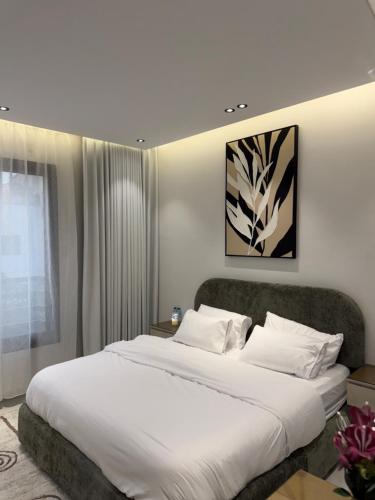a bedroom with a large bed with white sheets at Spacious Two-Bedroom Apartment with a Large Living Room, comfortable and well organized, perfect for a relaxing stay in Jeddah
