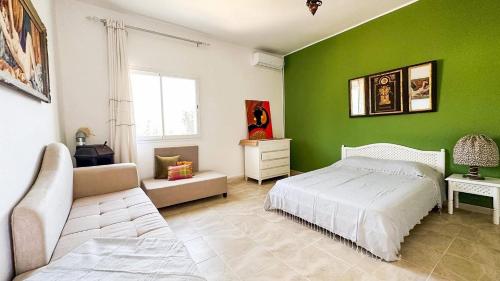 a bedroom with green walls and a bed and a couch at Dar Kmaar in Hammamet
