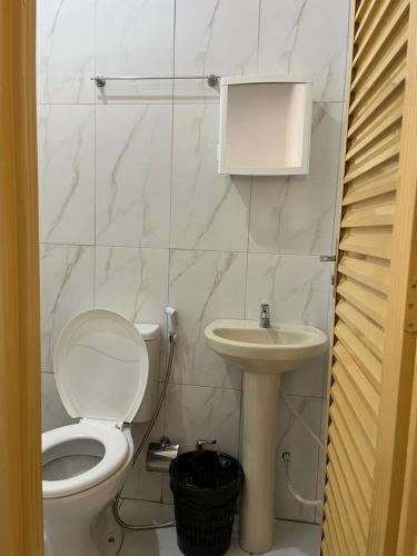 a white bathroom with a toilet and a sink at Cantinho da Naná in Cavalcante