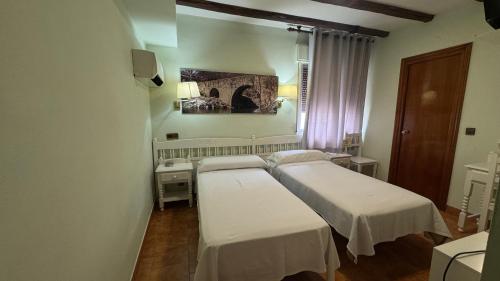 a hospital room with two beds and a window at Hosteria Conchi in Madrigal de la Vera