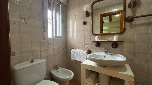 a bathroom with a sink and a toilet and a mirror at Hosteria Conchi in Madrigal de la Vera