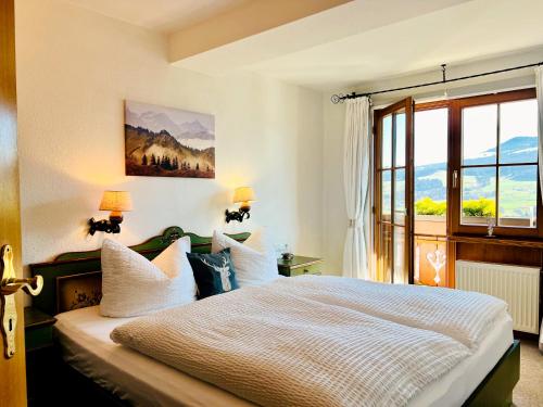 a bedroom with a large white bed with a window at Gästehaus Alpenruh in Fischen