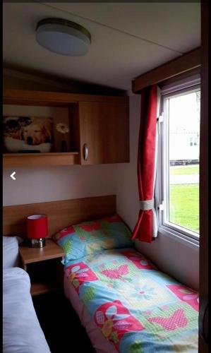 a bedroom with a bed and a window with a santa hat at Jaynes Holiday Caravan Marton Mere in Blackpool