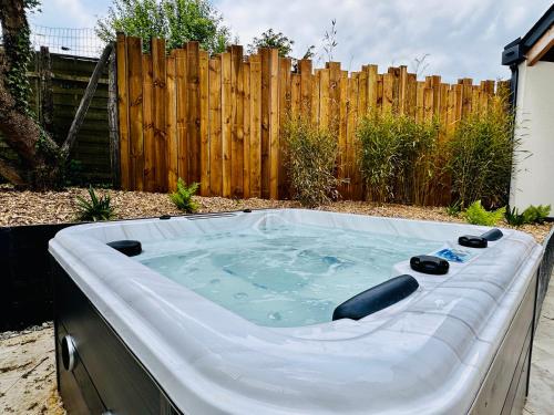 a hot tub in a backyard with a wooden fence at L'Instant Cottage, Chic et Spa près d'Amboise in Saint-Règle