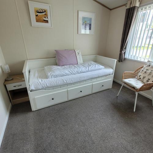 a white bed in a room with a chair at Trevella Lakeview Lodge in Newquay
