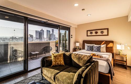 a bedroom with a bed and a couch and a balcony at Kukun Tonala 30 Roma in Mexico City