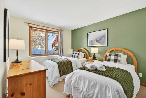 two beds in a room with green walls at Haut-Bois by Rendez-Vous Mont-Tremblant in Mont-Tremblant
