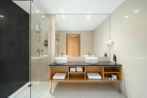 a bathroom with two sinks and a shower at Agua Hotels Riverside in Ferragudo