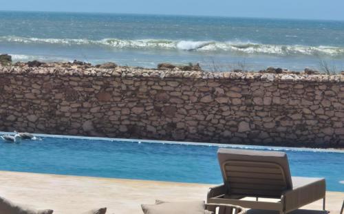 a chair sitting next to a swimming pool next to the ocean at Anima Ocean Lodges in Essaouira