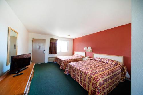 a hotel room with two beds and a flat screen tv at Superior Suites Phoenix Mesa in Mesa