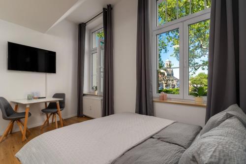 a bedroom with a bed and a desk and two windows at Litzi's zentrales Apartment mit Parkplatz in Hockenheim