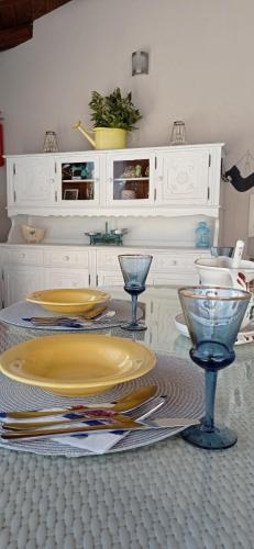 a table with yellow plates and wine glasses on it at Casa Providenca in Kaštelir