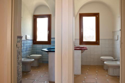a bathroom with two toilets and two windows at Le Ville Le Saline in Palau