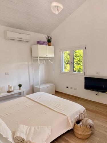 a white bedroom with a large bed and a window at Casetta a Lago in Onno