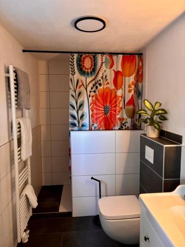 a bathroom with a toilet and a flower shower curtain at Ferienwohnung Rosengarten in Einbeck