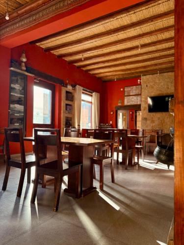 a dining room with red walls and wooden tables and chairs at Hotel Refugio Del Sol in La Quiaca