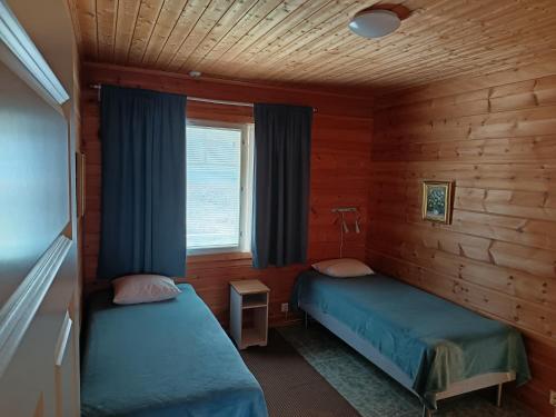 a bedroom with two beds in a wooden cabin at Taljatie Apartments in Rovaniemi