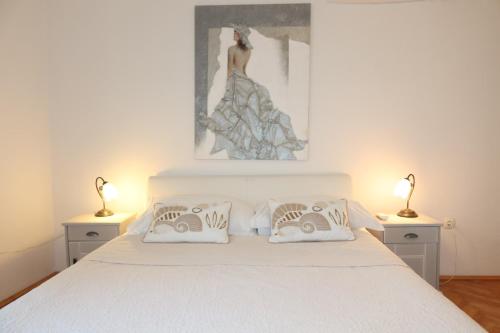 a bedroom with a white bed with two lamps at Apartman Perina in Trogir