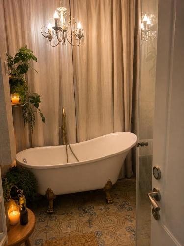 a bath tub in a bathroom with a chandelier at Cozy flat near park in Netanya