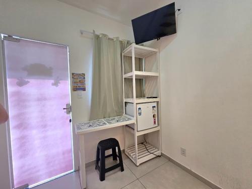 a room with a tv and a shelf with a chair at Pousada Bahamas Sc in Penha
