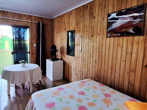 a bedroom with a bed and a table in it at Cabana com Estacionamento ll Internet l Nomade Digital ll Táxi Fácil II Fogão Peq ll Quiosque Churrasqueira ll 5km da ERS-030 Km 88 ll 7Km da Prefeitura l Câmara Mun I IFRGS II 7,2Km UFRGS Litoral II l 12km-Praias in Osório