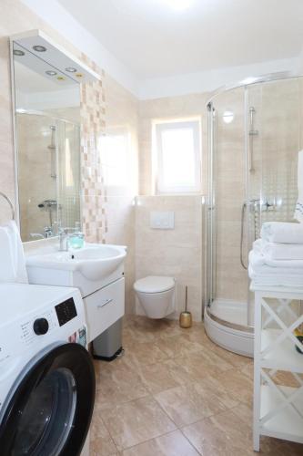 a bathroom with a washing machine and a sink at Apartman Perina in Trogir