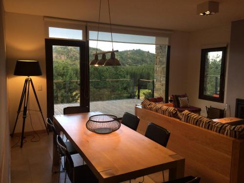 comedor con mesa y ventana grande en Golf y Polo Apartment en San Martín de los Andes