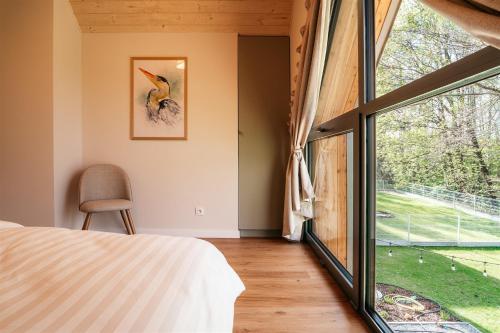 a bedroom with a bed and a large window at Domki Poleskie Stodoły in Stare Załucze