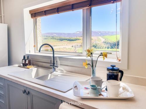a kitchen sink with a tray with cups and a window at Nether Clashnoir, Glenlivet in Knockandhu