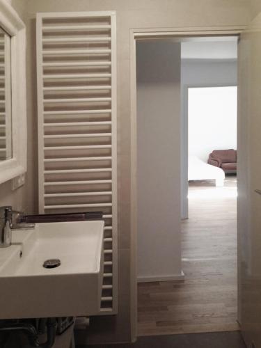 a white bathroom with a sink and a bedroom at Apartment Ammersee in Dießen am Ammersee