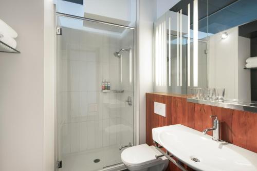 ein Badezimmer mit Dusche, Toilette und Waschbecken in der Unterkunft Hôtel Alt Quartier DIX30 in Brossard