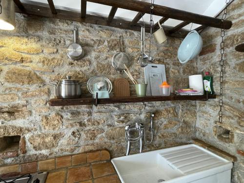 a kitchen with a sink and a stone wall at Casa Collina - Grottino in Pisticci