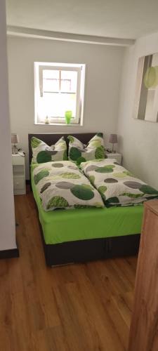 a bedroom with a bed with green sheets and a window at Ferienwohnung am Kirchberg Europa-Park Spassbad-Rulantica-Schwarzwald ,Frankreich, in Ettenheim