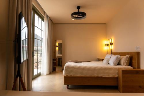 a bedroom with a bed and a large window at Nangi Hotel Boutique in Valle de Guadalupe