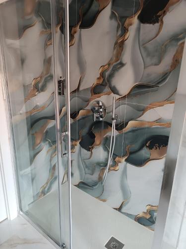 a glass shower with a painting on the wall at Maison MariEtt - Smart & Living Suites - in Troia