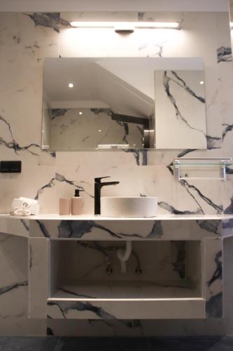 a bathroom with a sink and a mirror at Zeus Cosmos Apartments in Lourdata
