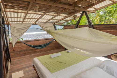 a hammock in a room with a view of the beach at El Vijo Surf in Nuquí