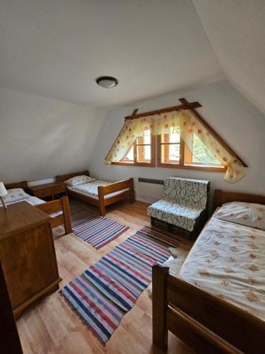 a attic room with two beds and a window at Chalupa pod Skleným Vŕškom in Huty