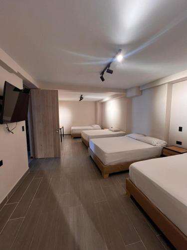a room with three beds and a ceiling fan at Hotel Gran Imperio la 69 in Medellín