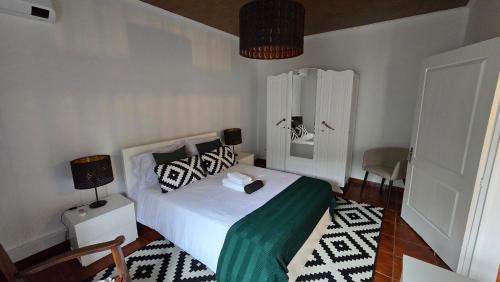 a bedroom with a bed with a green blanket and pillows at ALgarvia in Algarvia
