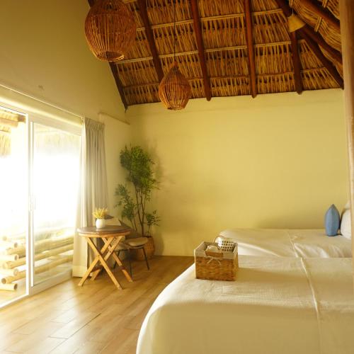 a bedroom with two beds and a table and a window at Hotel Estrella de Mar in Zipolite