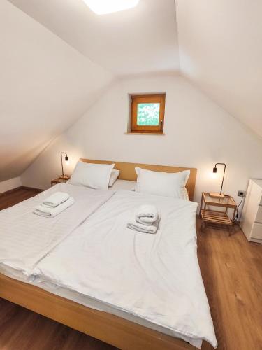 a bedroom with a large white bed with two towels on it at Silent Orchard in Naklo
