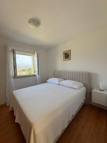 a white bed in a bedroom with a window at Apartments Mikecin in Novigrad Dalmatia
