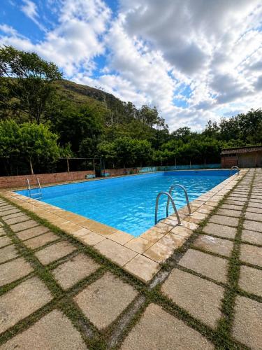 a large blue swimming pool with trees in the background at Pousada Quinta de Areal in Areal