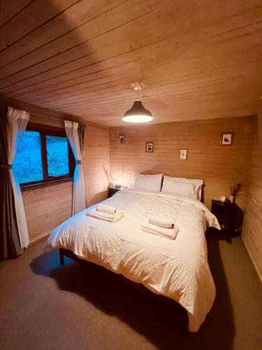 a bedroom with a large bed in a wooden room at Cosy Log Cabin in Machynlleth - Wales - Wifi & Parking in Machynlleth