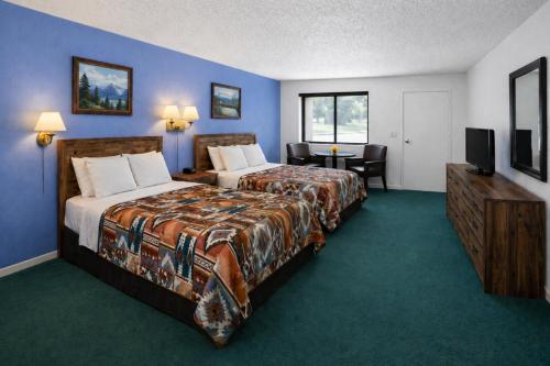 a hotel room with two beds and a television at Branding Iron Motel in Chama